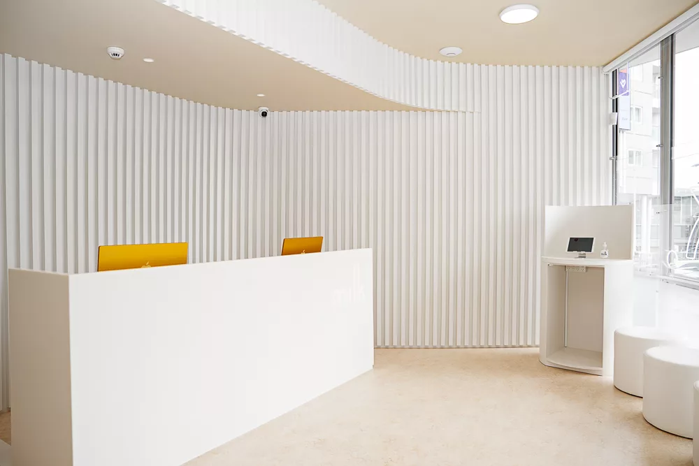 Reception area with fluted white walls and check-in kiosk at Milk Orthodontics