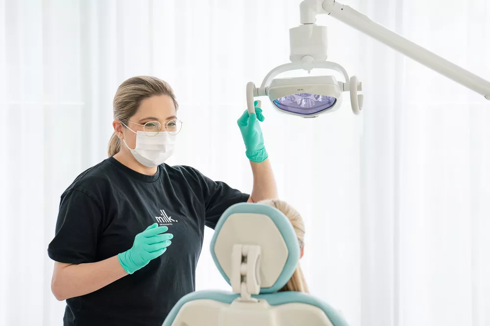 A Milk Orthodontics team member in mask and gloves adjusting the treatment light