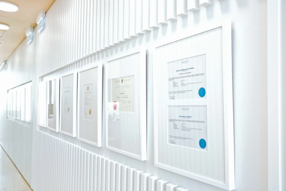 Wall of framed specialist orthodontic qualifications at Milk Orthodontics in Newmarket, a short drive from Remuera